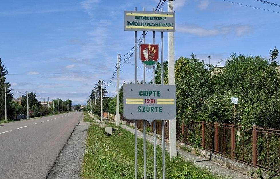 Sign marking the entrance to the village of Surte, with the name repeated in Hungarian. Zakarpattia Oblast, Ukraine